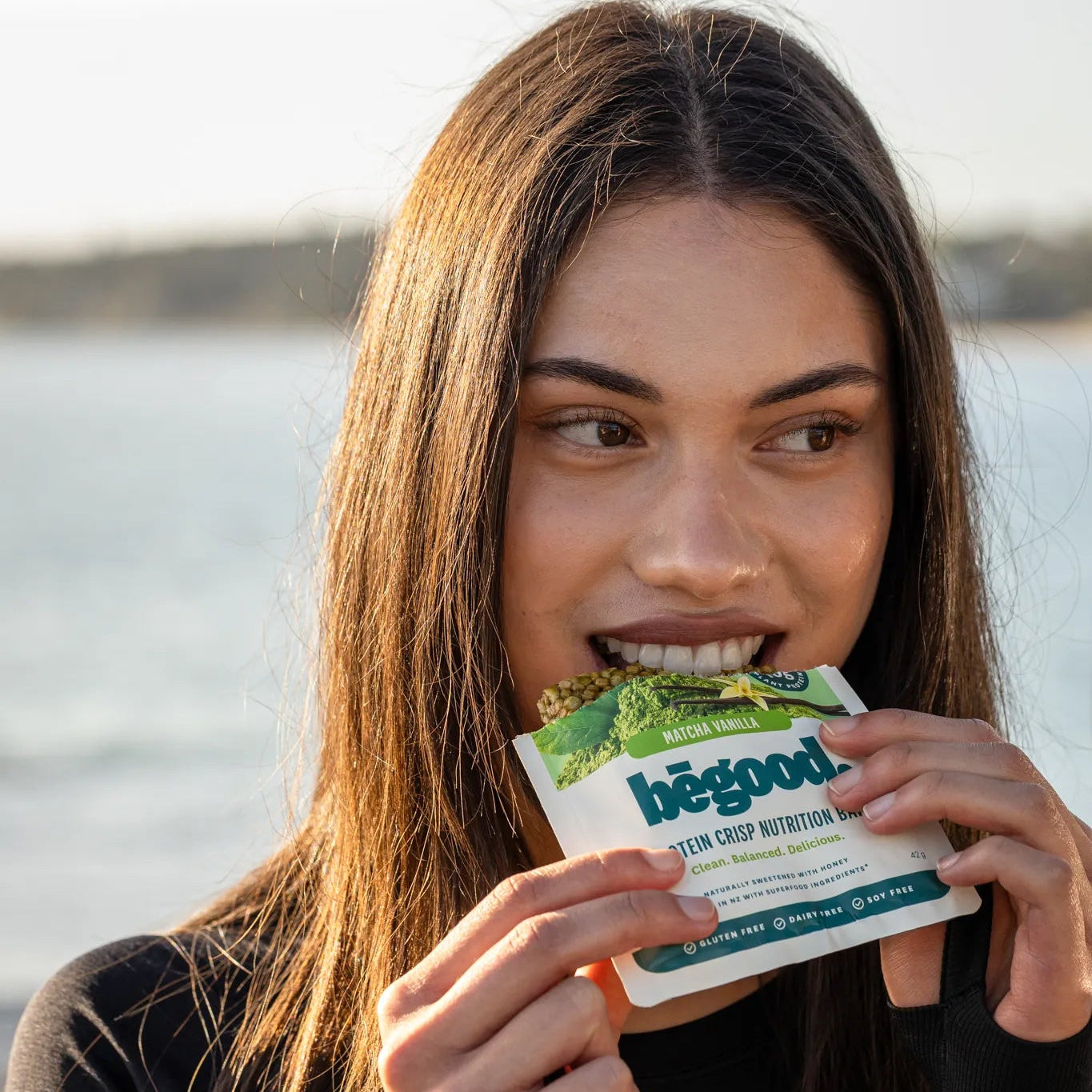 Woman holding a 'begood' product by a body of water