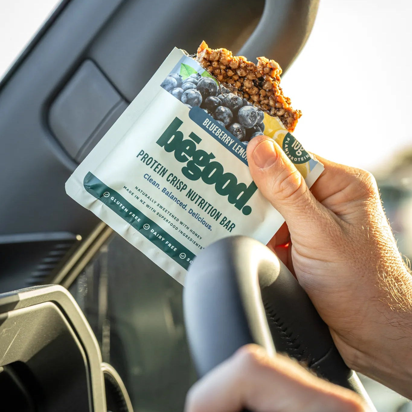 Person holding a begood protein crisp nutrition bar inside a car.